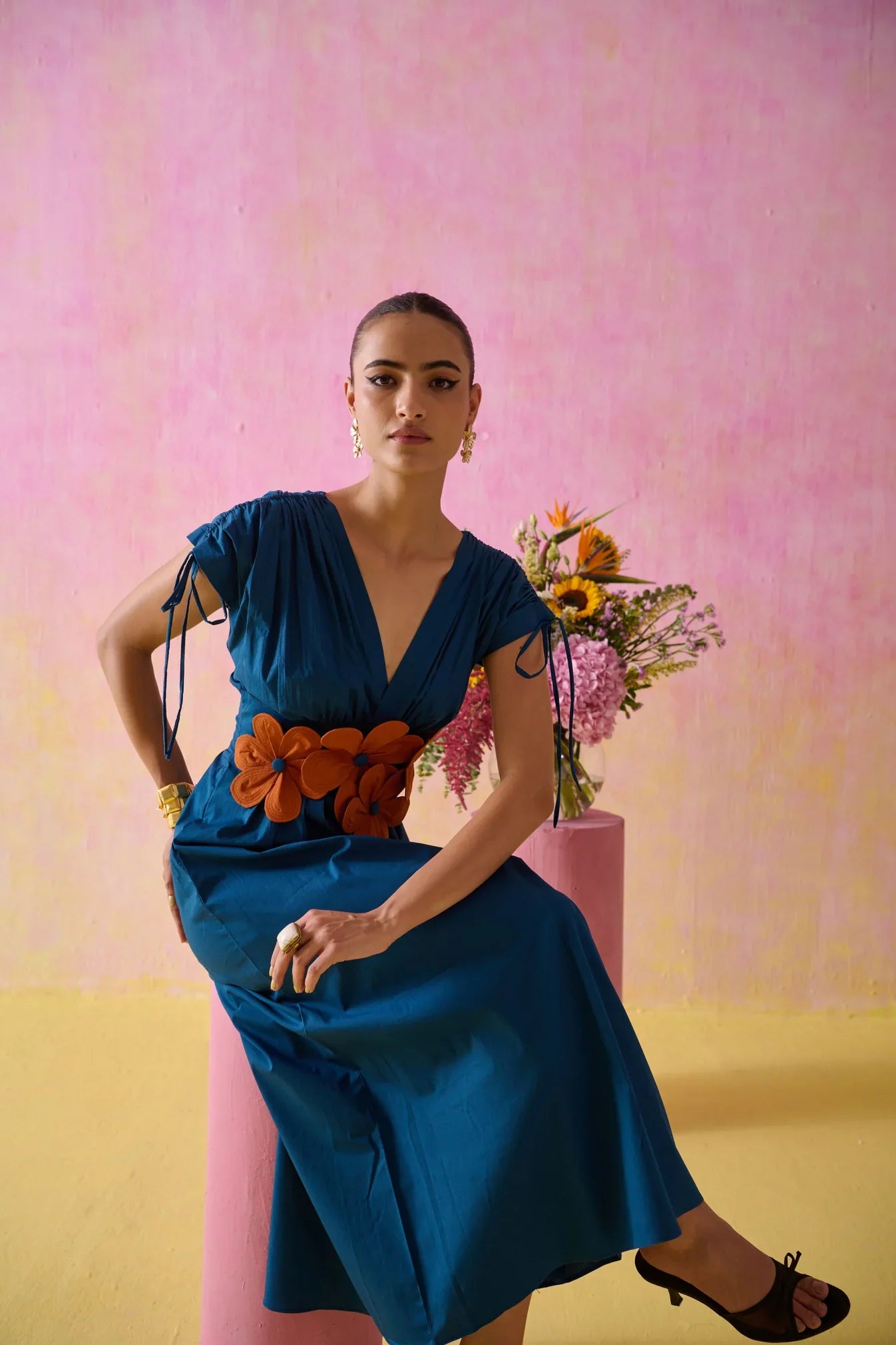 Woman in a teal wrap dress with a fabric-flower belt
